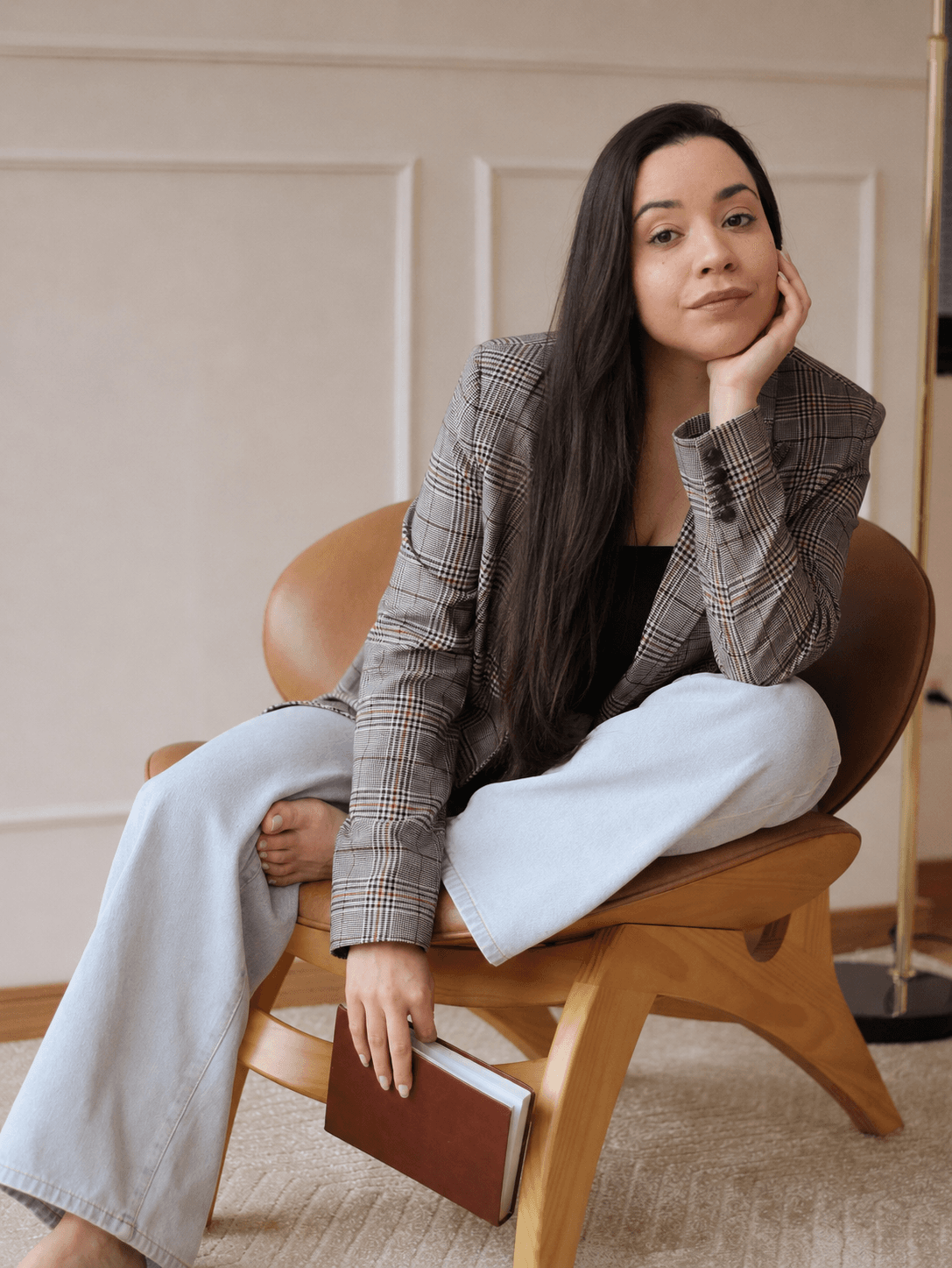 Letícia Paranhos sentada em uma poltrona, com um livro na mão